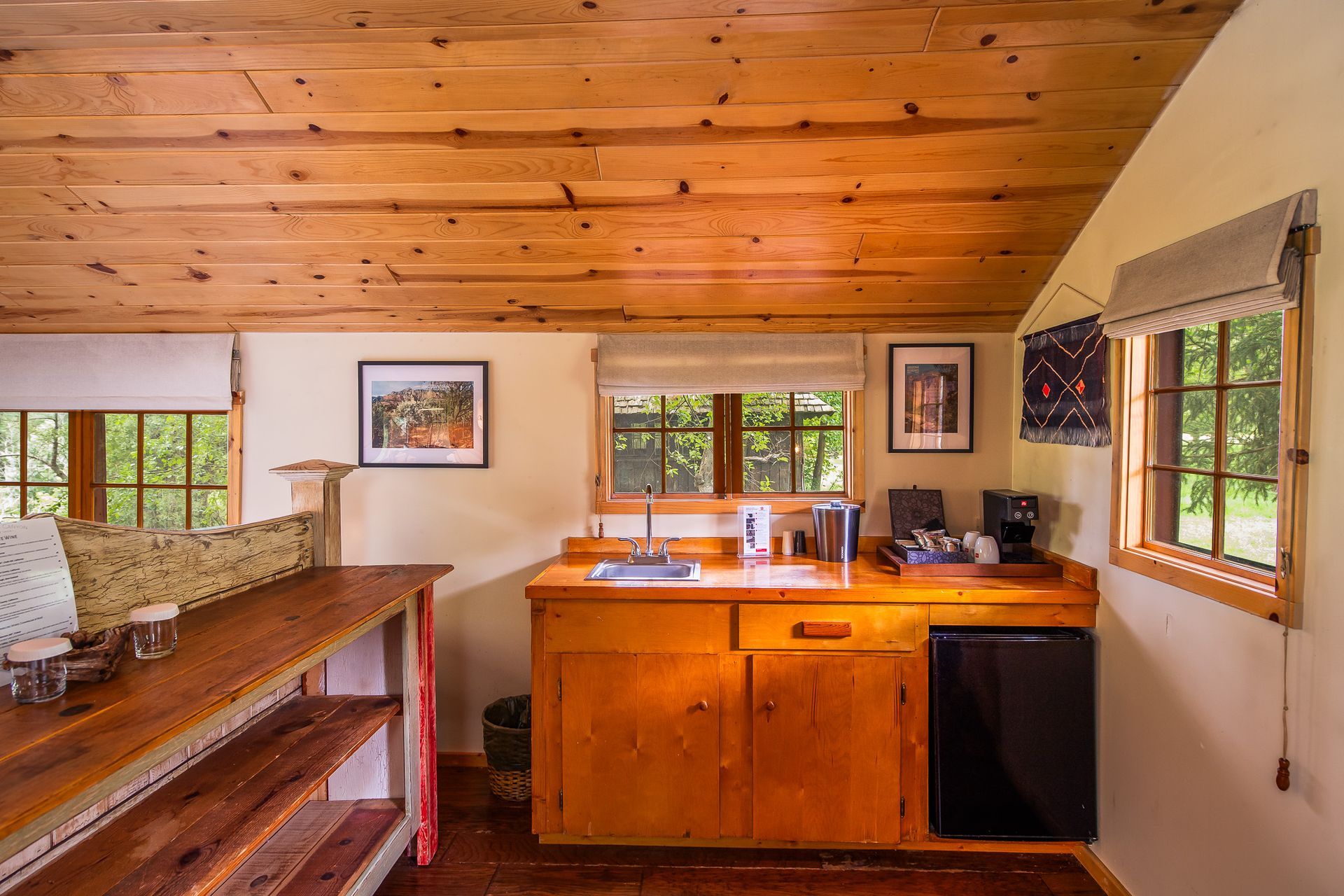 Warm rustic kitchen with wood cabinets, slanted ceiling, and windows letting in daylight