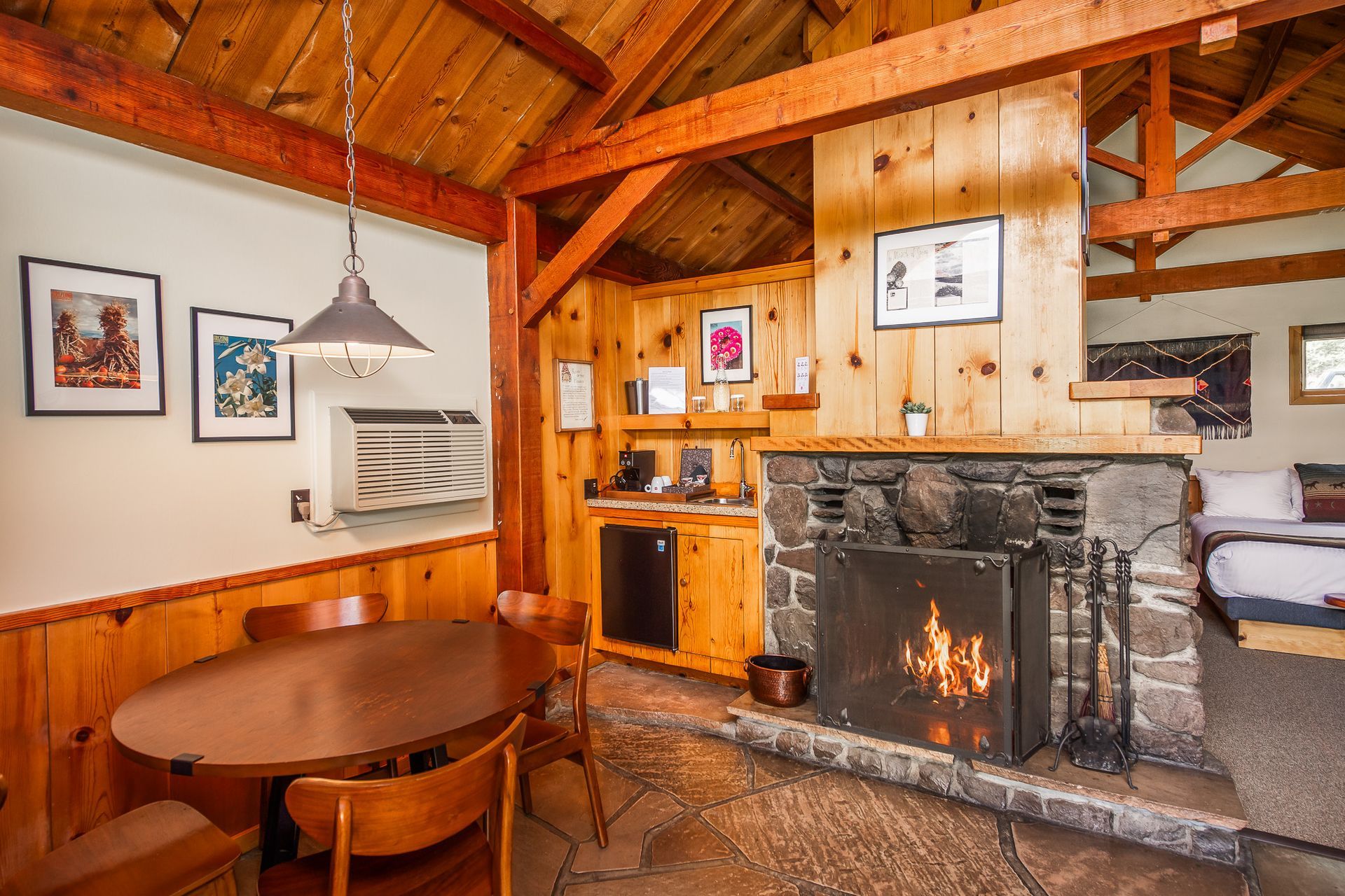 Cozy cabin dining area with wooden table, stone fireplace, and warm wood beams