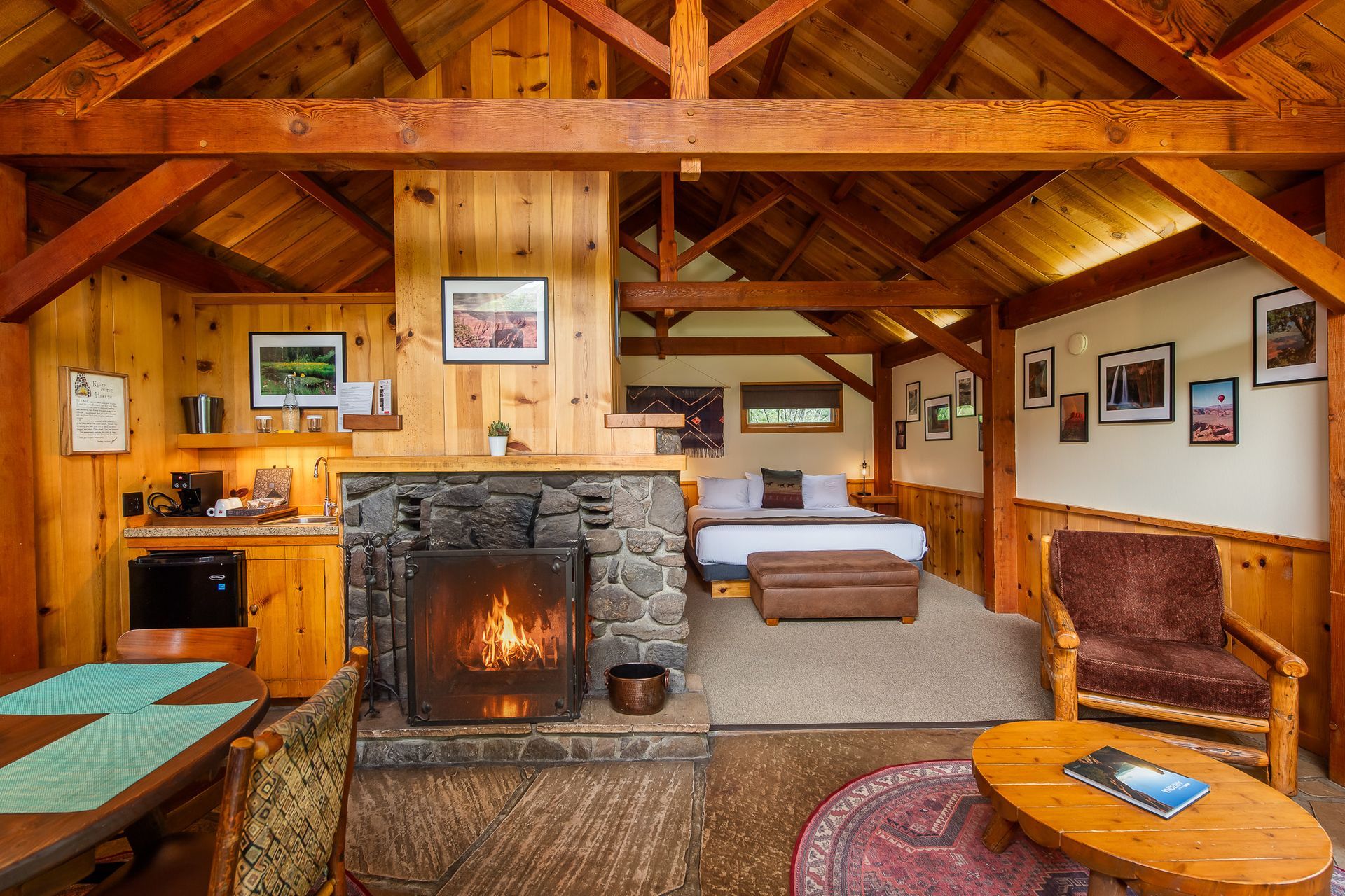 Rustic cabin interior with stone fireplace, wood beams, sofa, and warm orange lighting