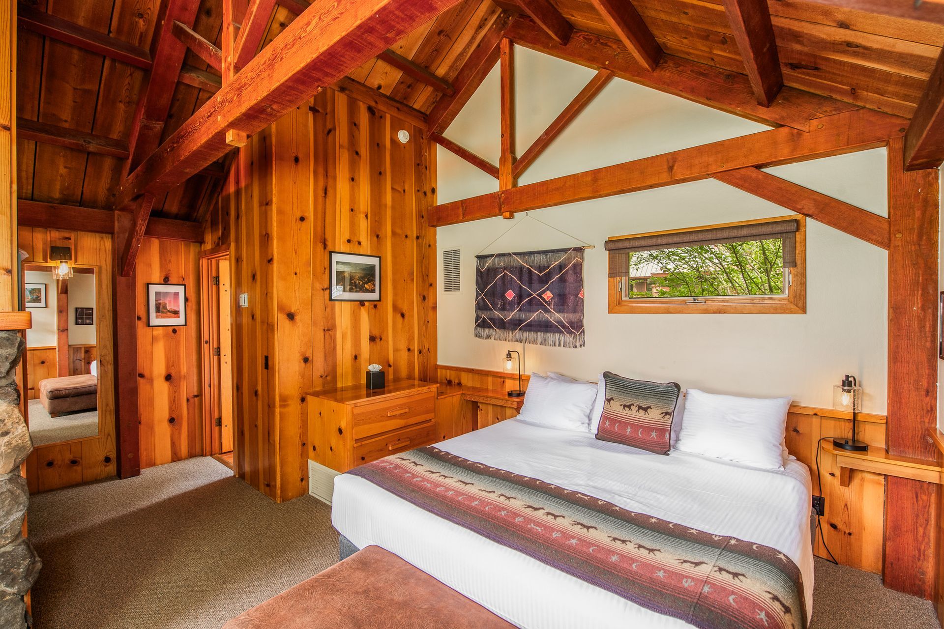 Wood-paneled bedroom with a canopy bed, rustic beams, and a window view
