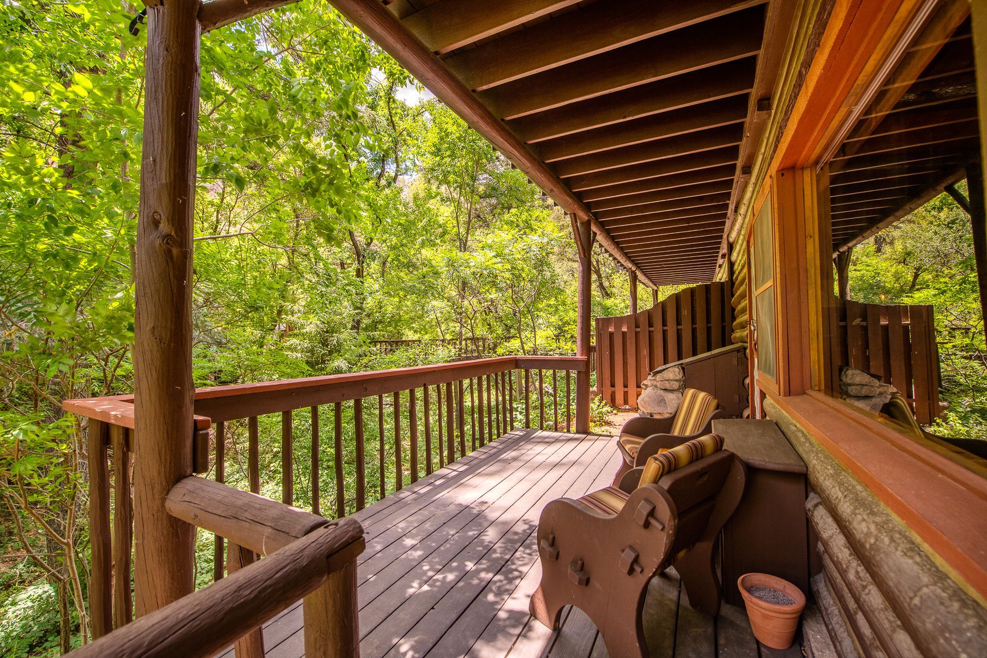Wooden cabin porch with rocking chairs and a railing overlooking green trees