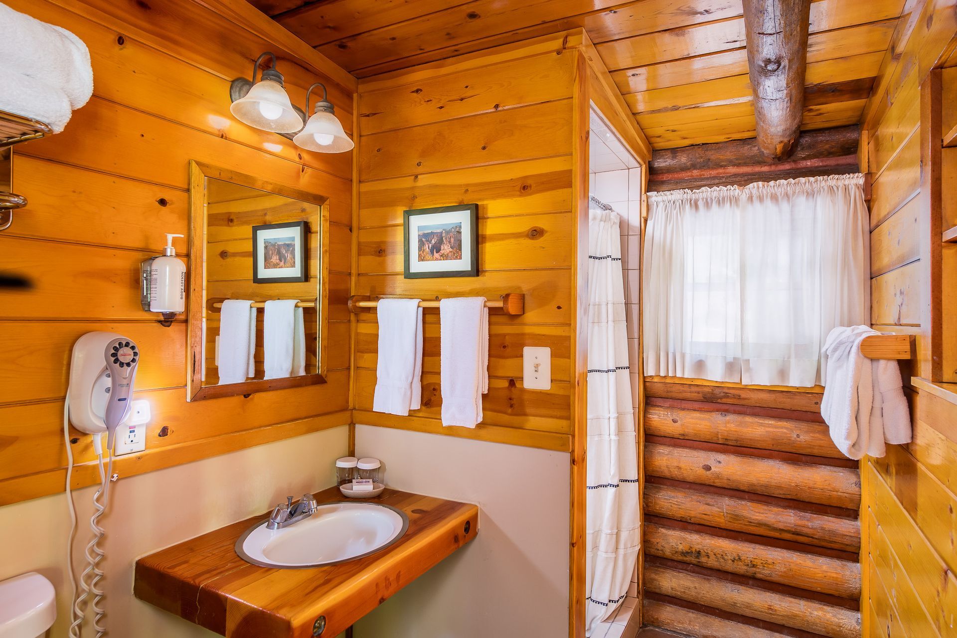 Wood-paneled cabin bathroom with sink, mirror, towel rack, and striped shower curtain
