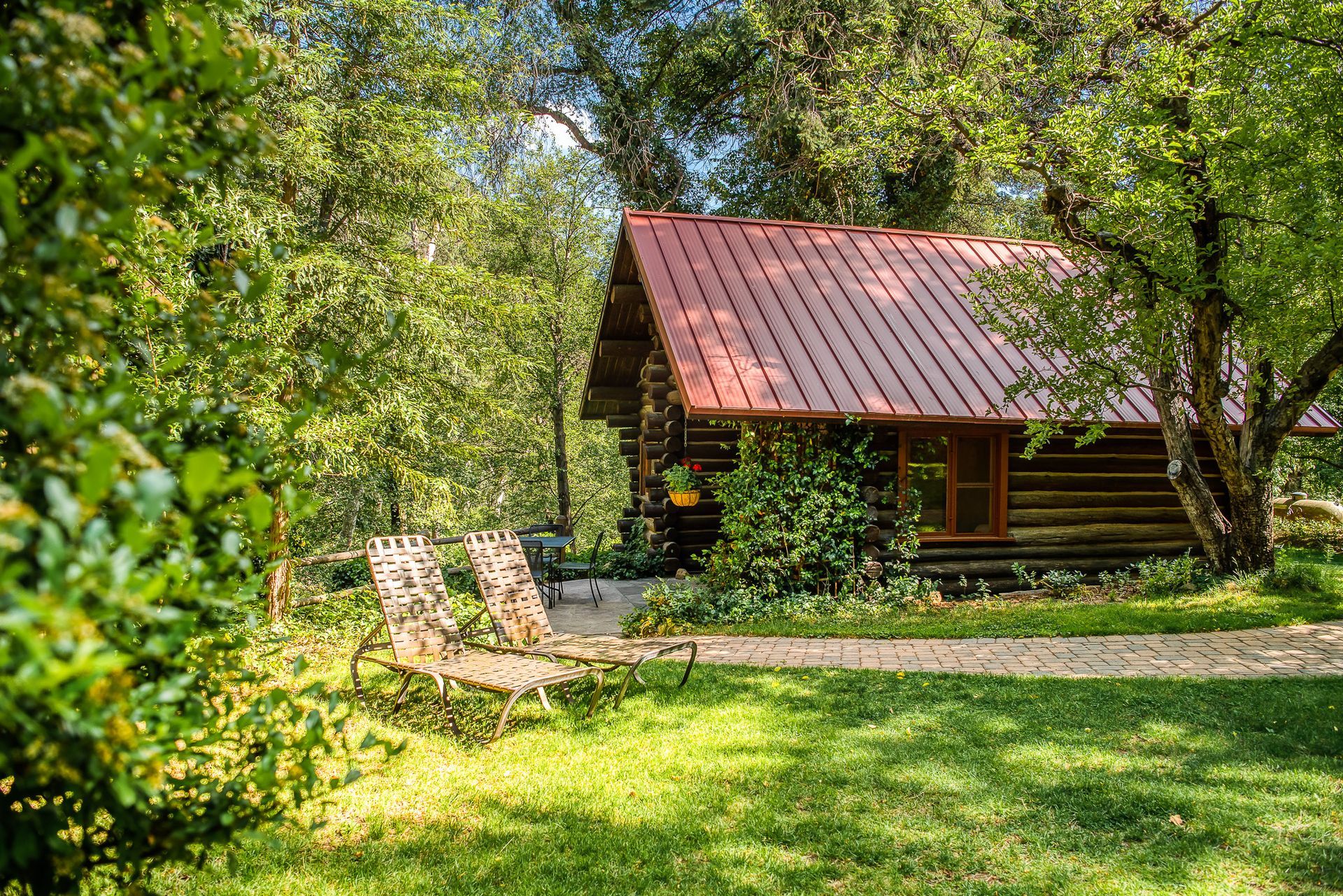 Wooden cabin with red roof nestled in a sunny green forest clearing