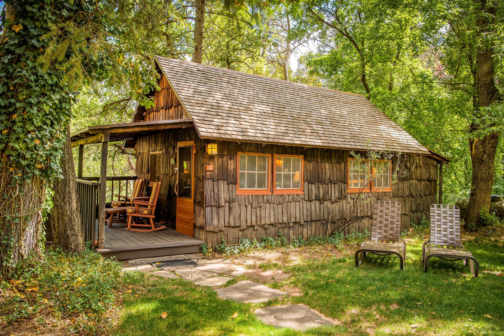 Rustic wooden cabin with a shingled roof in a leafy forest clearing