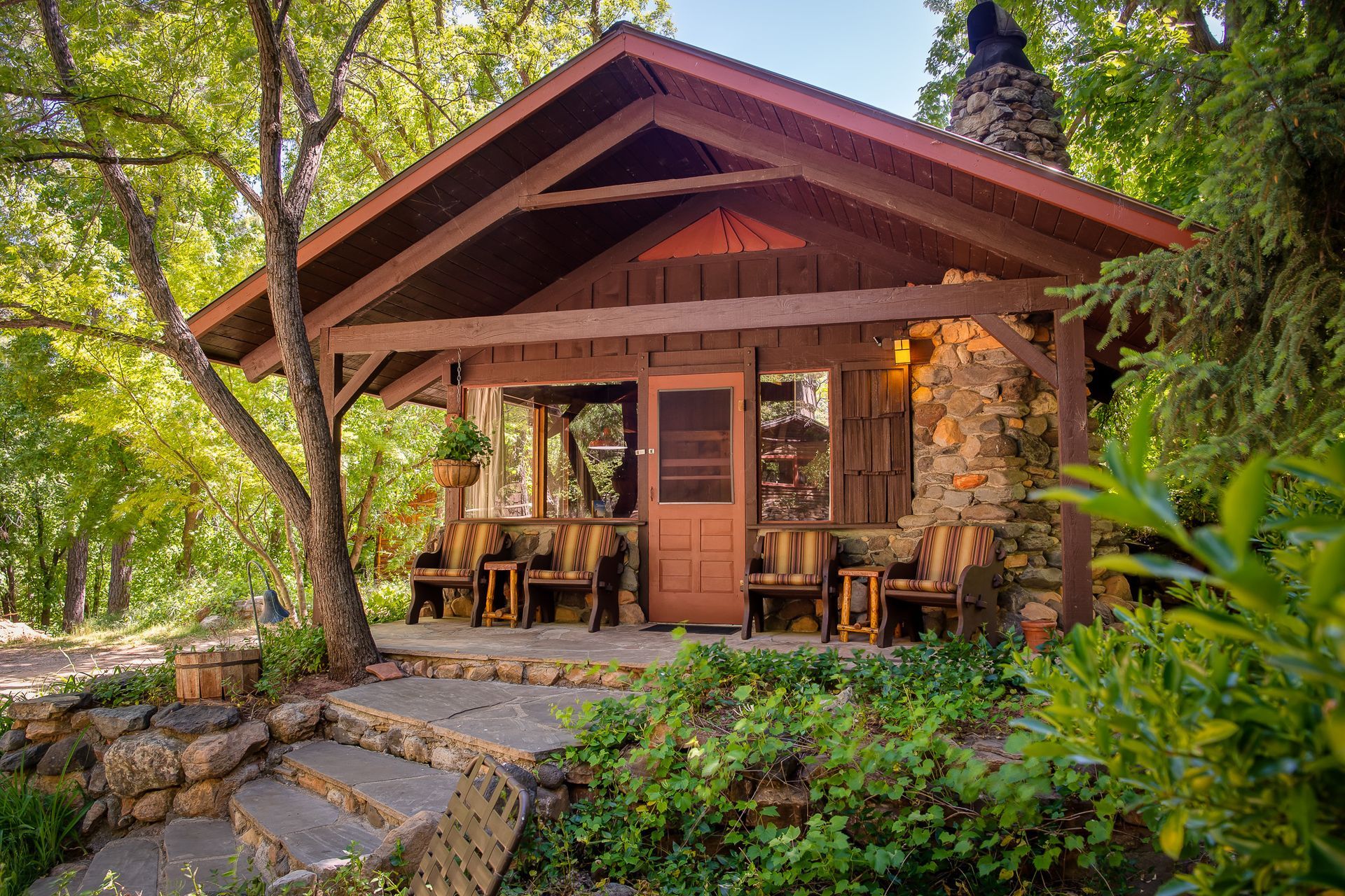 Cozy wooden cabin porch in a lush forest, with stone steps and warm sunlight