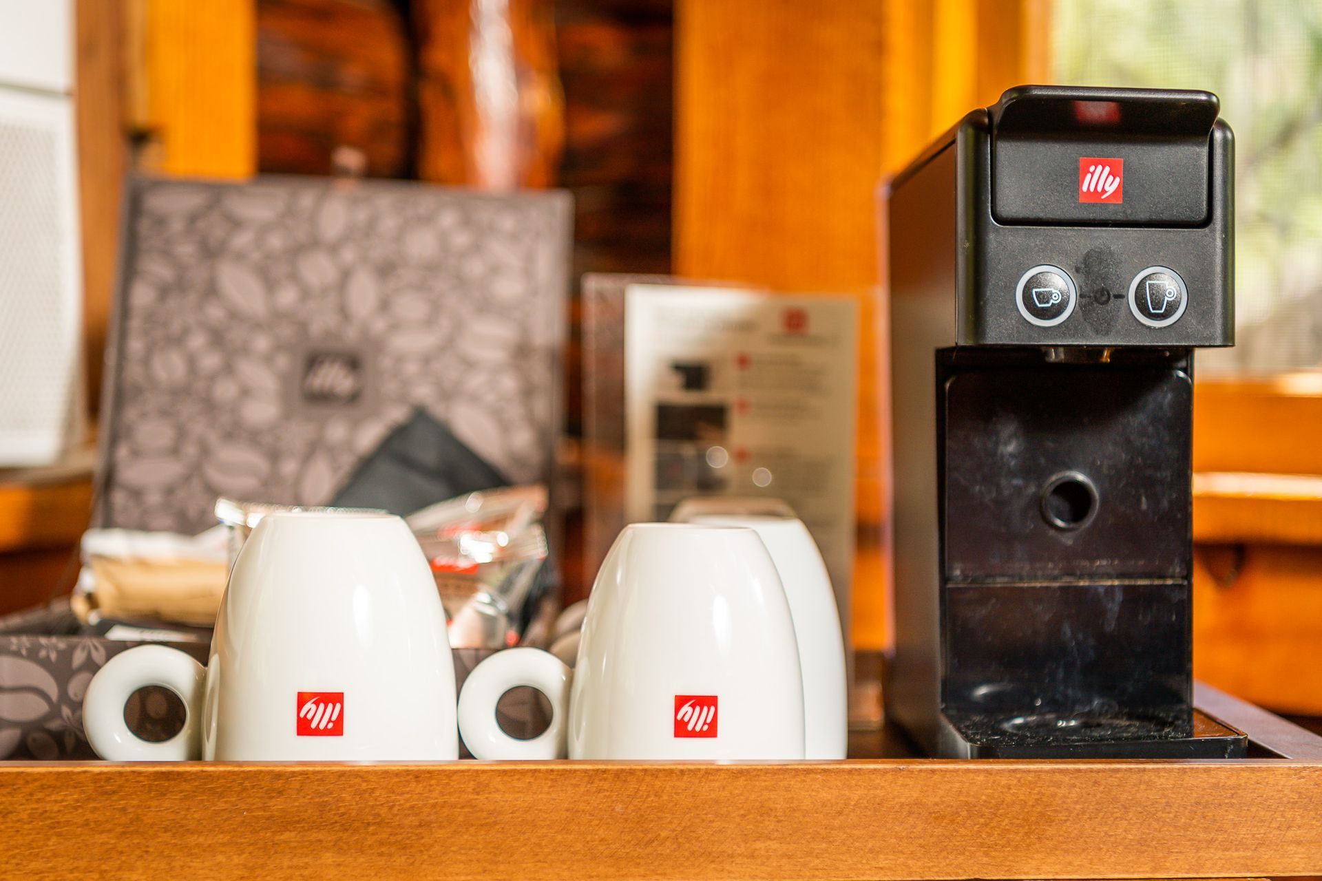 Coffee mugs and a black espresso machine on a countertop, with boxes in the background