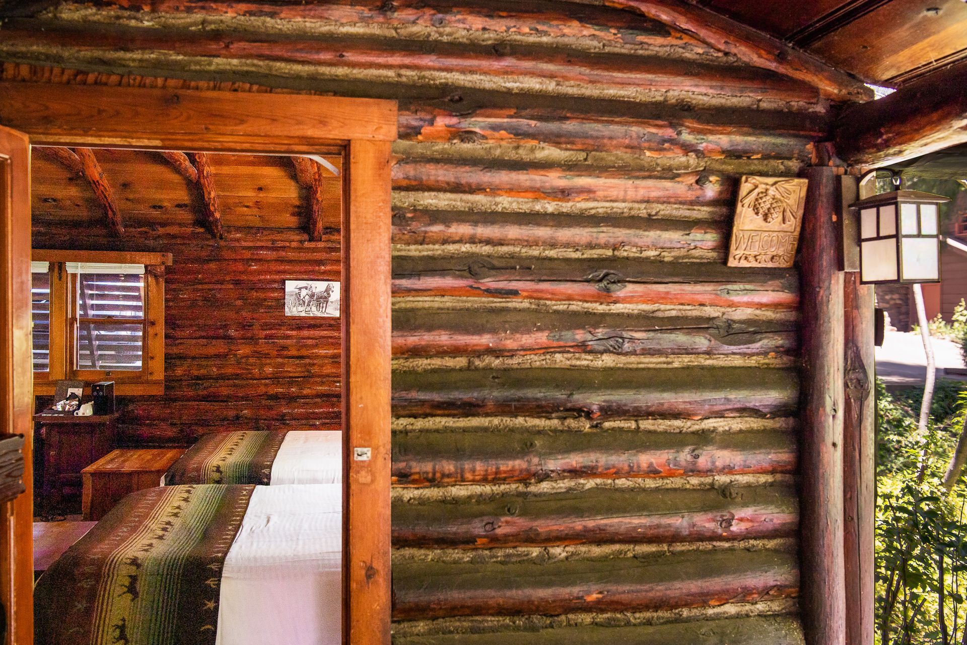 Log cabin wall with doorway, showing a bunk bed inside and log construction details