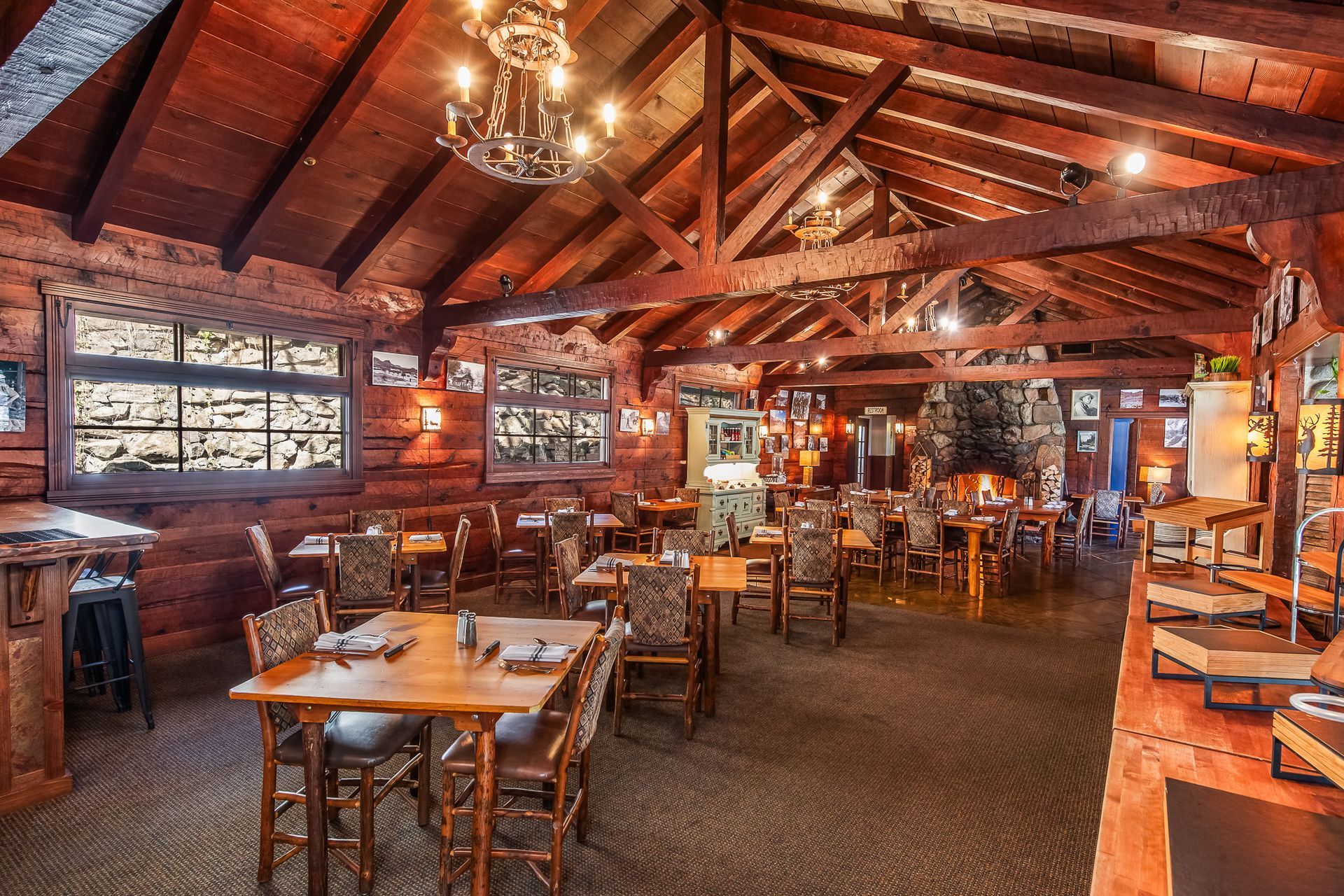 Rustic restaurant interior with wooden beams, warm lighting, and neatly set dining tables