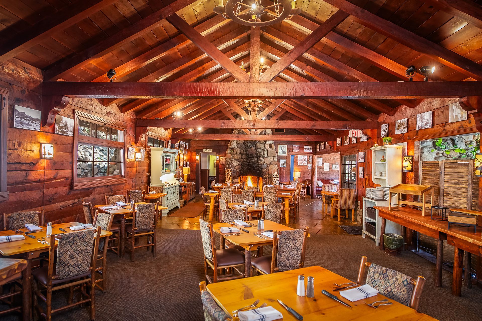 Cozy rustic restaurant interior with wooden beams, warm lighting, and neatly set tables and chairs