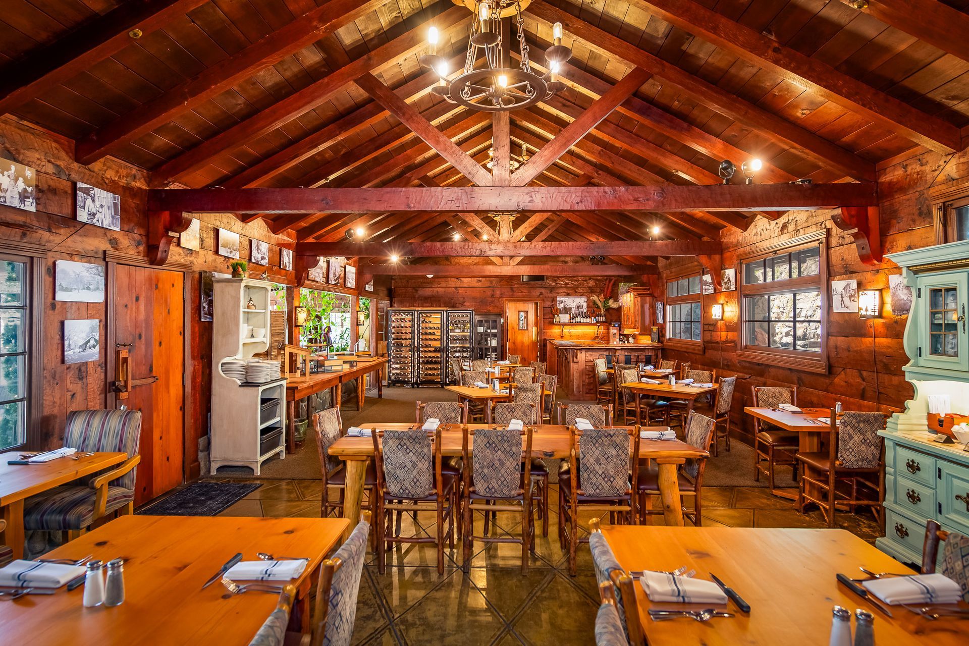 Rustic log cabin restaurant interior with wooden tables, chairs, and warm amber lighting