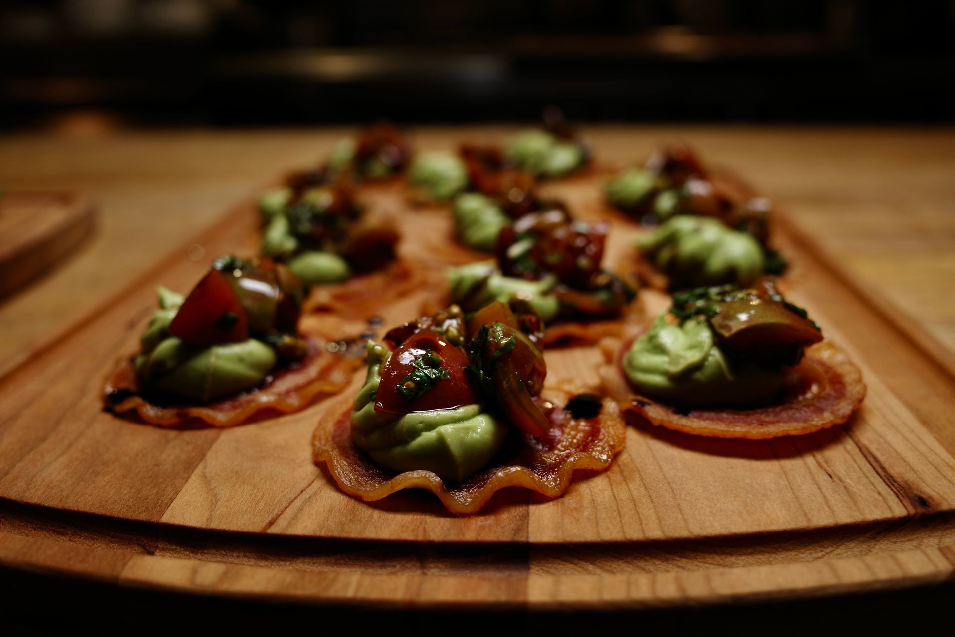 Assorted mini tarts topped with strawberries and green fruit on a wooden serving board