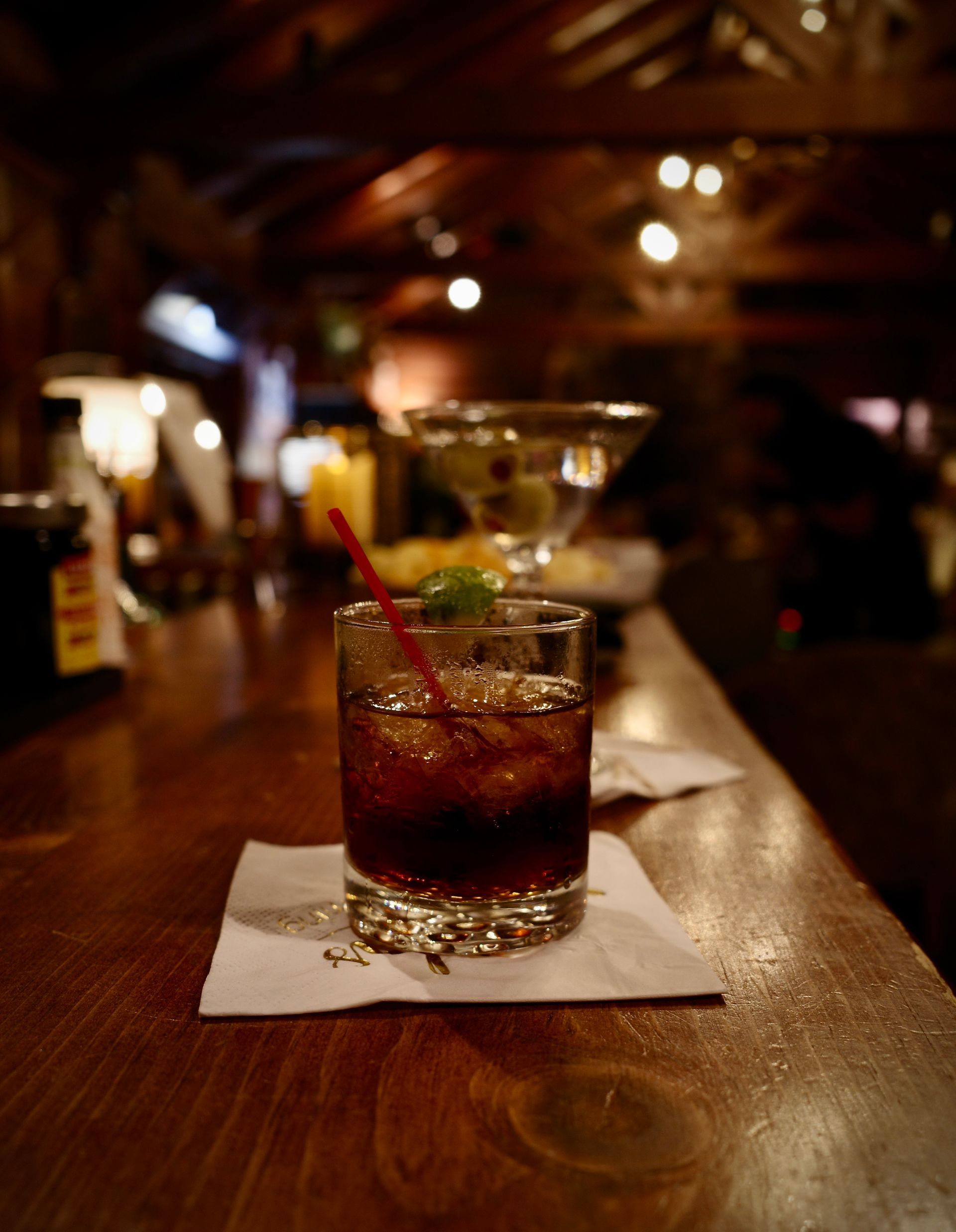 Cocktail with a cherry on a bar counter in a dimly lit lounge