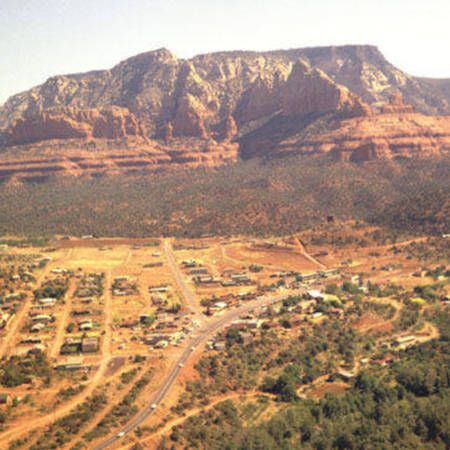 Aerial view of a desert town below a red sandstone mesa and rocky mountain ridge