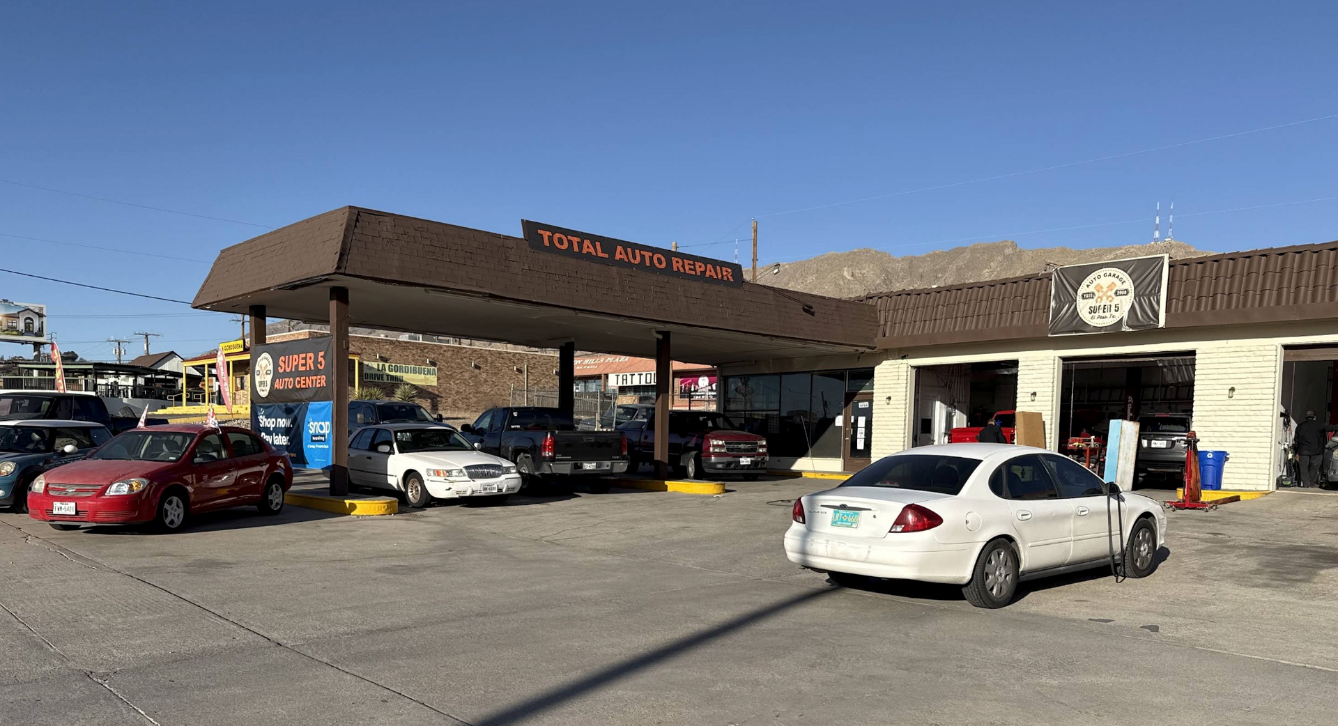Parking lot outside a restaurant with several cars under a covered entrance on a sunny day | Super 5 Auto Center