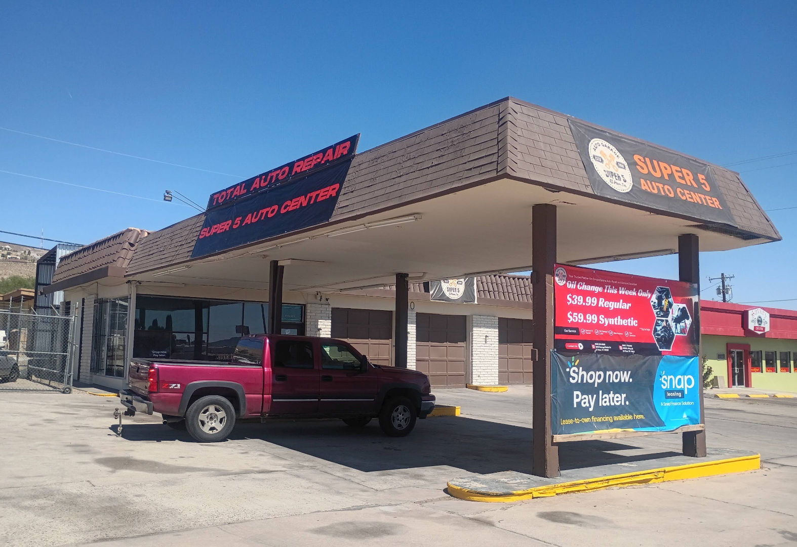 Drive-thru storefront with a maroon SUV parked under the awning on a sunny day. | Super 5 Auto Center