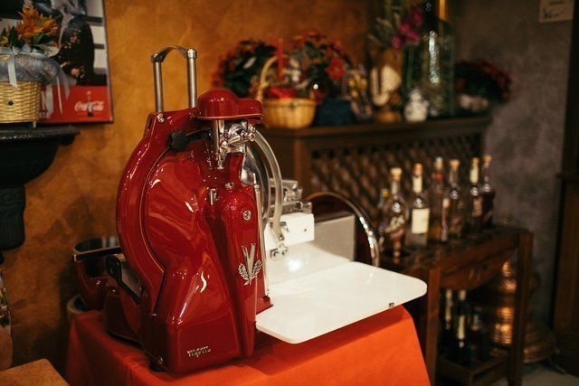 Macchina da caffè espresso vintage rossa su un tavolo arancione in un accogliente ambiente da bar o cucina.