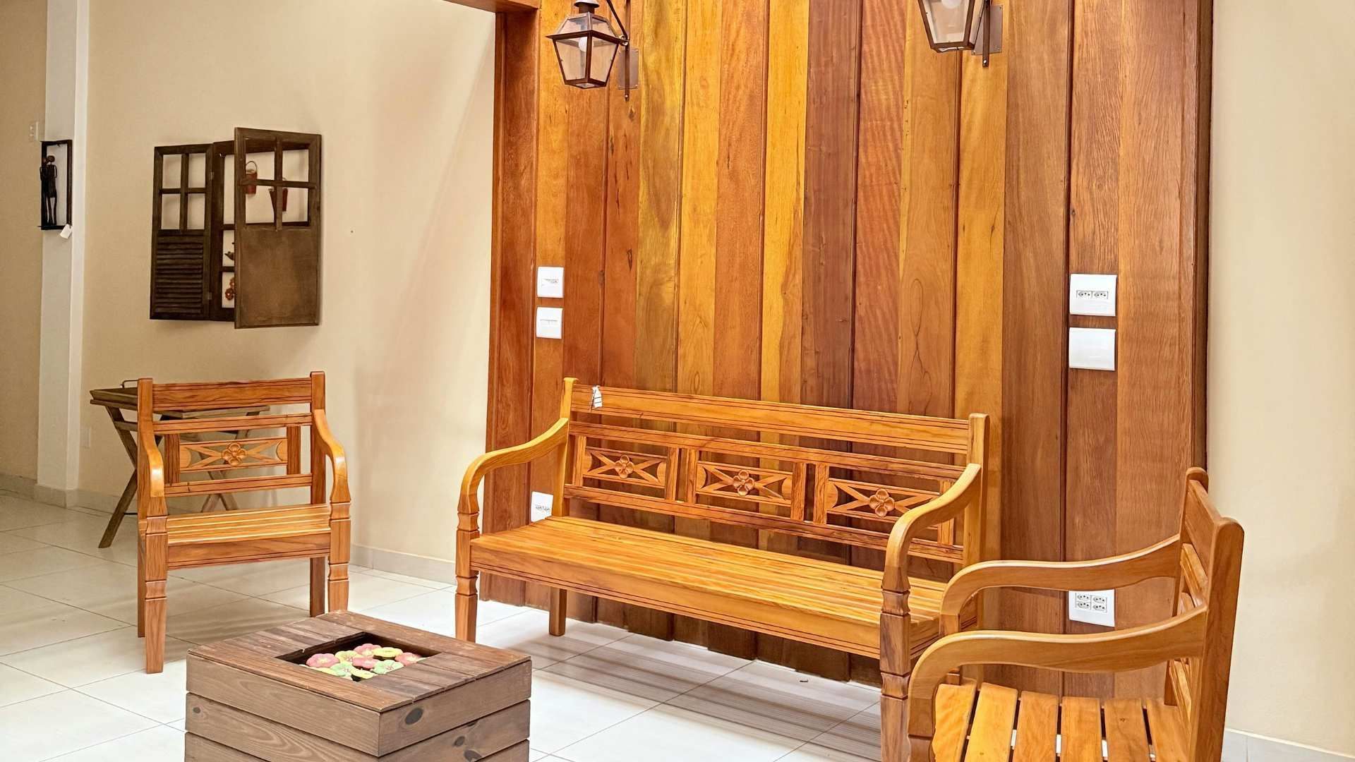 Wooden bench and chairs in a bright room with tan curtains and a small table