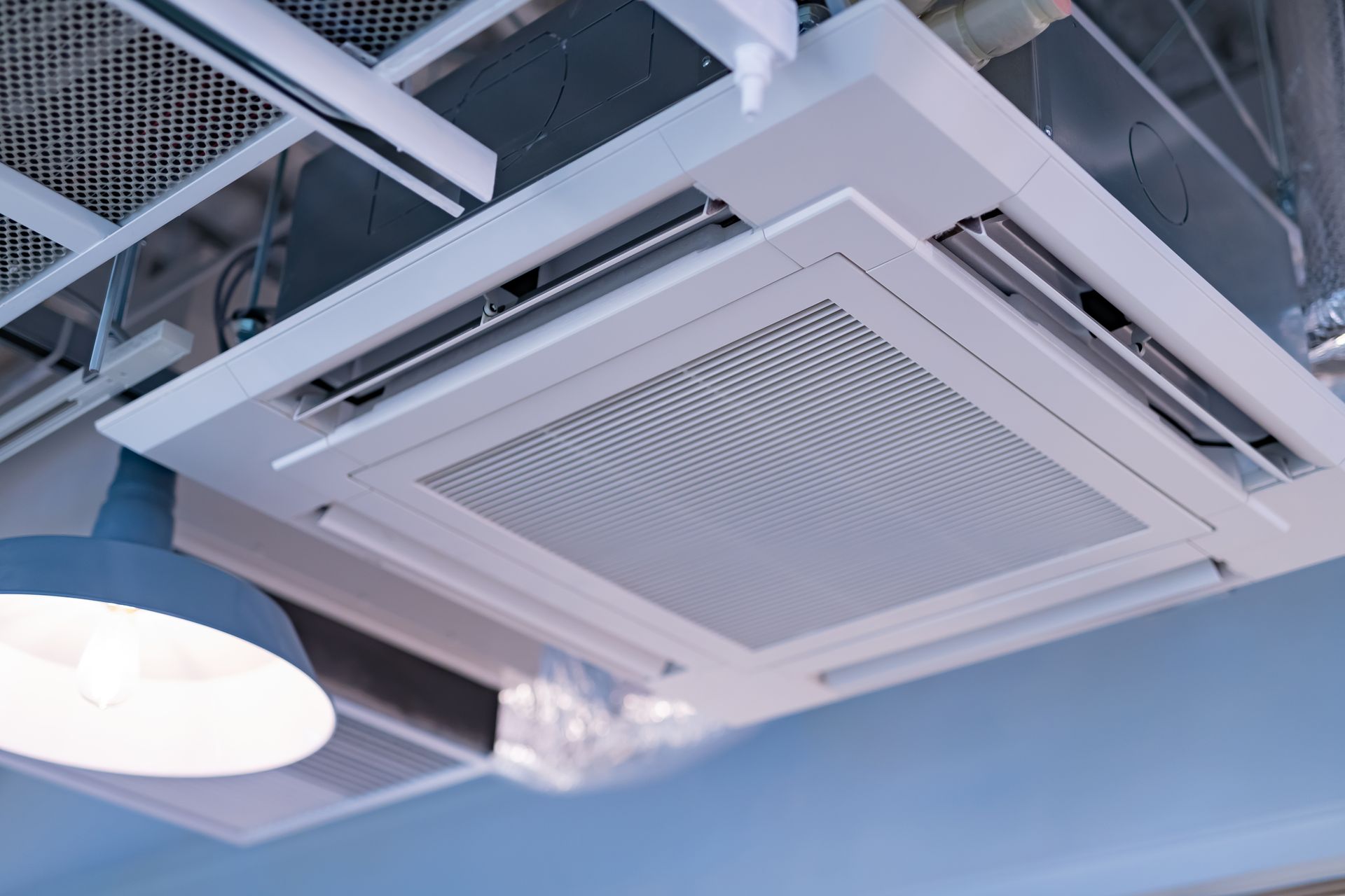 Ceiling-mounted white air conditioner in a blue office interior