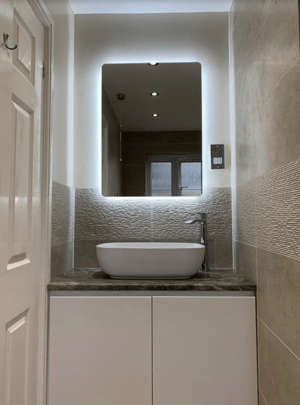 Modern bathroom vanity with vessel sink, mirror, and gray textured tile walls