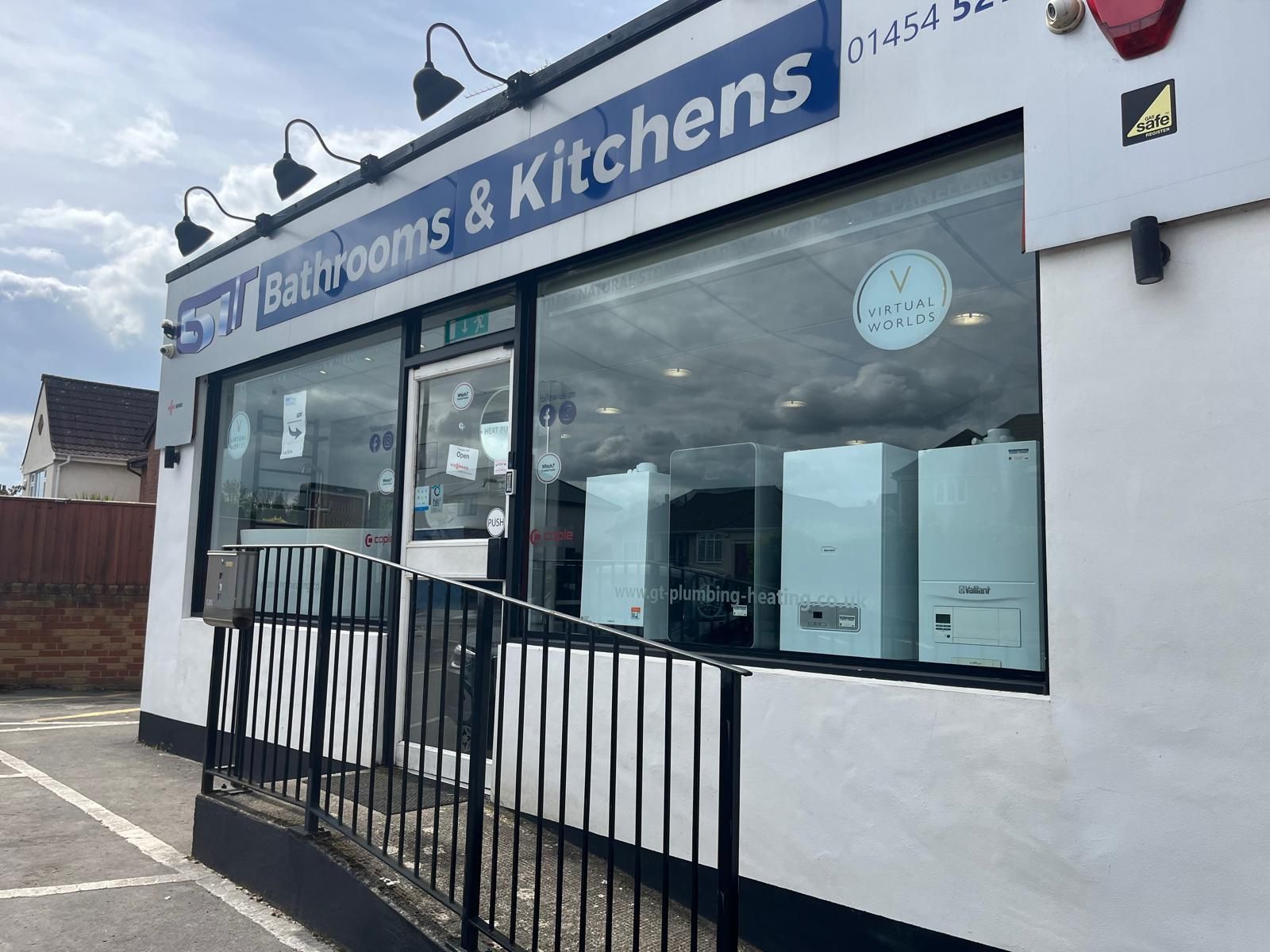 Storefront for “Bathrooms & Kitchens” with large windows and a black metal ramp railing.
