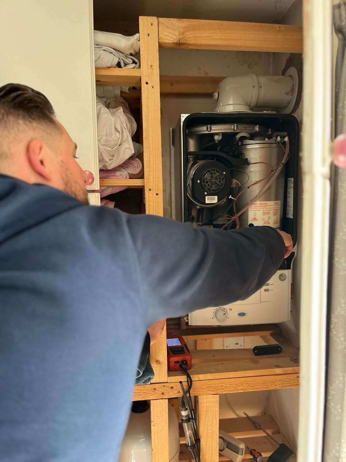 Technician inspecting a wall-mounted tankless water heater in a closet
