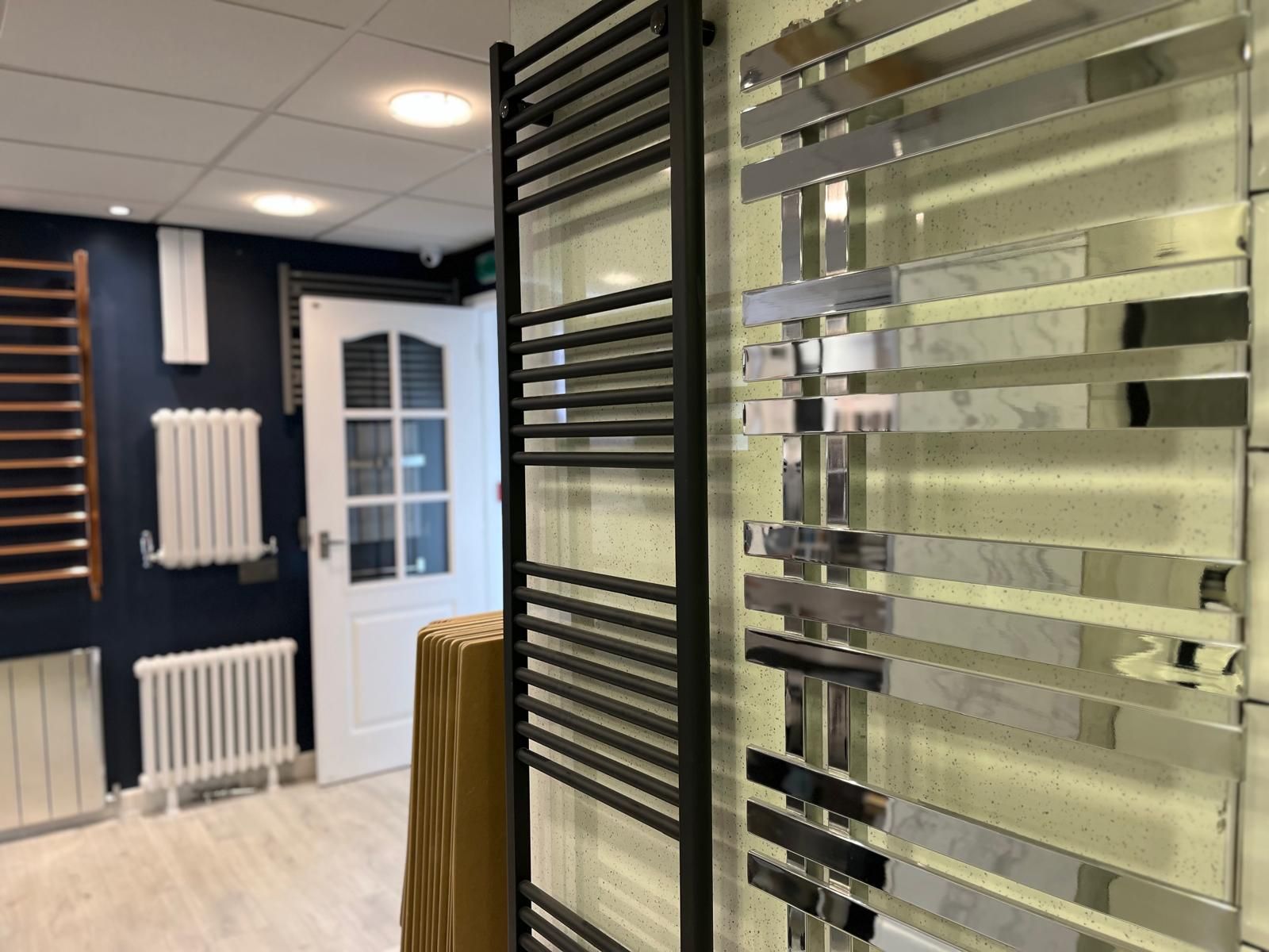 Modern showroom with wall-mounted towel radiators and glass shower enclosures in dark blue and white décor