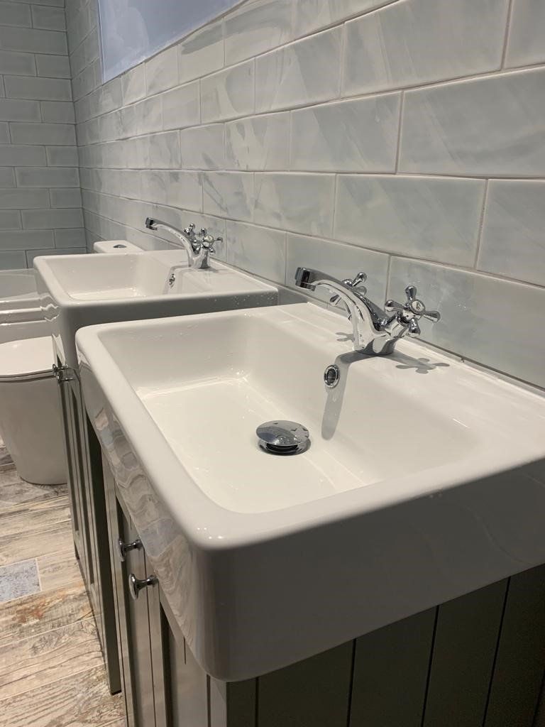 Two white wall-mounted sinks in a tiled public restroom with chrome faucets.