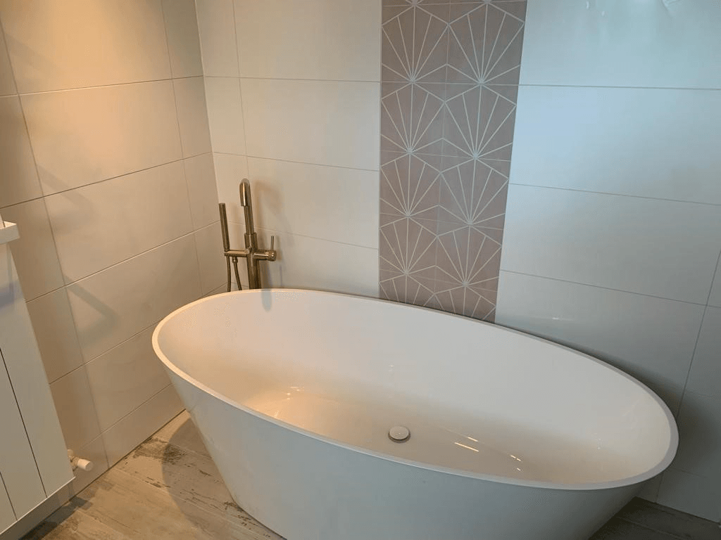 Modern bathroom with a freestanding white oval bathtub and patterned tile accent wall.