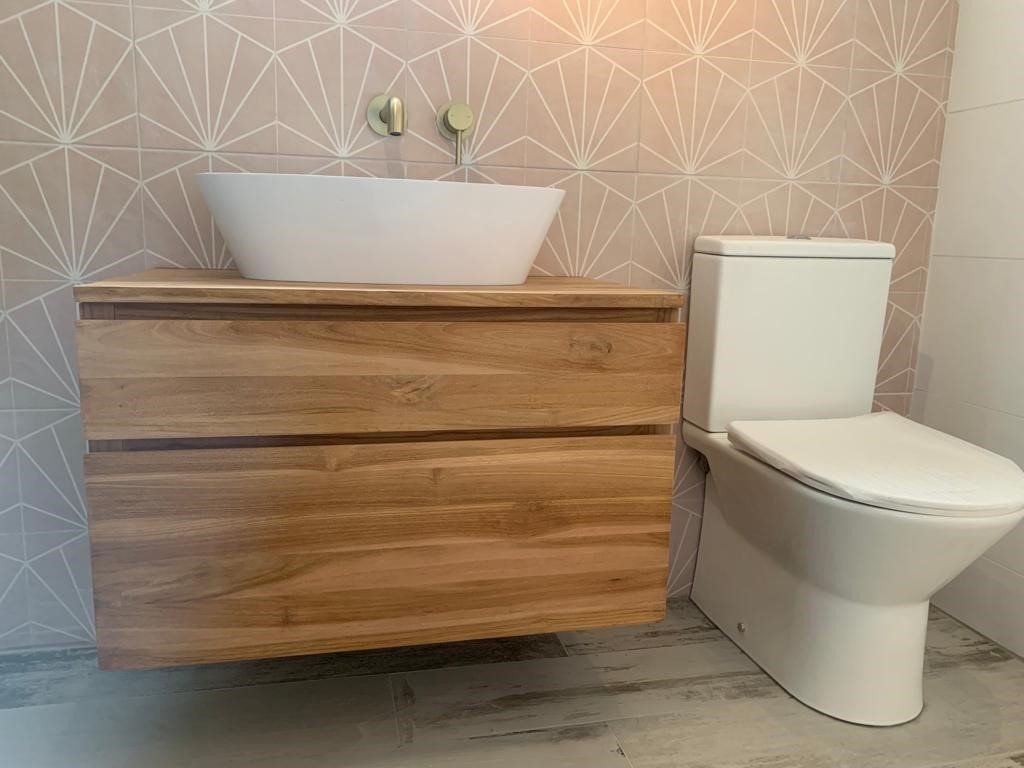 Modern bathroom with wood vanity, white vessel sink, toilet, and patterned wallpaper