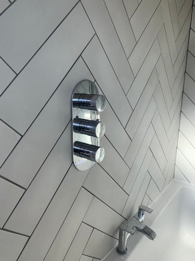 White tiled shower wall with chrome faucet and built-in soap/shampoo niche