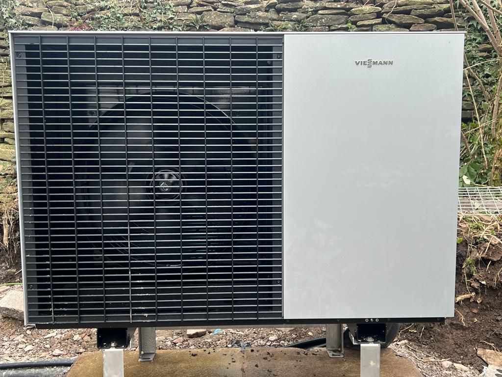 Outdoor HVAC unit with black grille and gray side panel on a concrete pad
