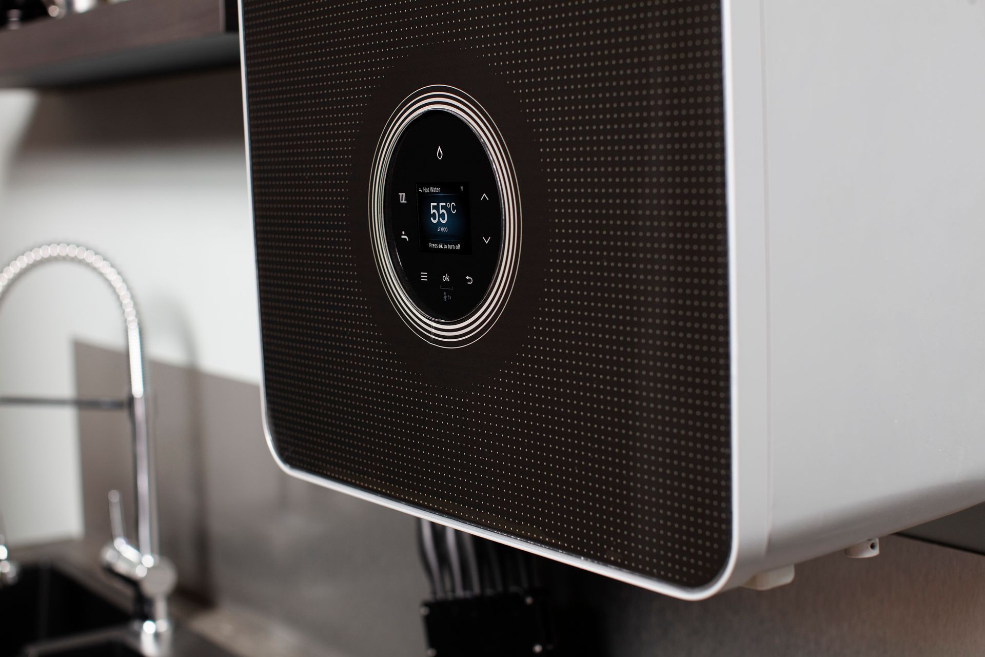 Close-up of a silver espresso machine with a black front panel and circular display.