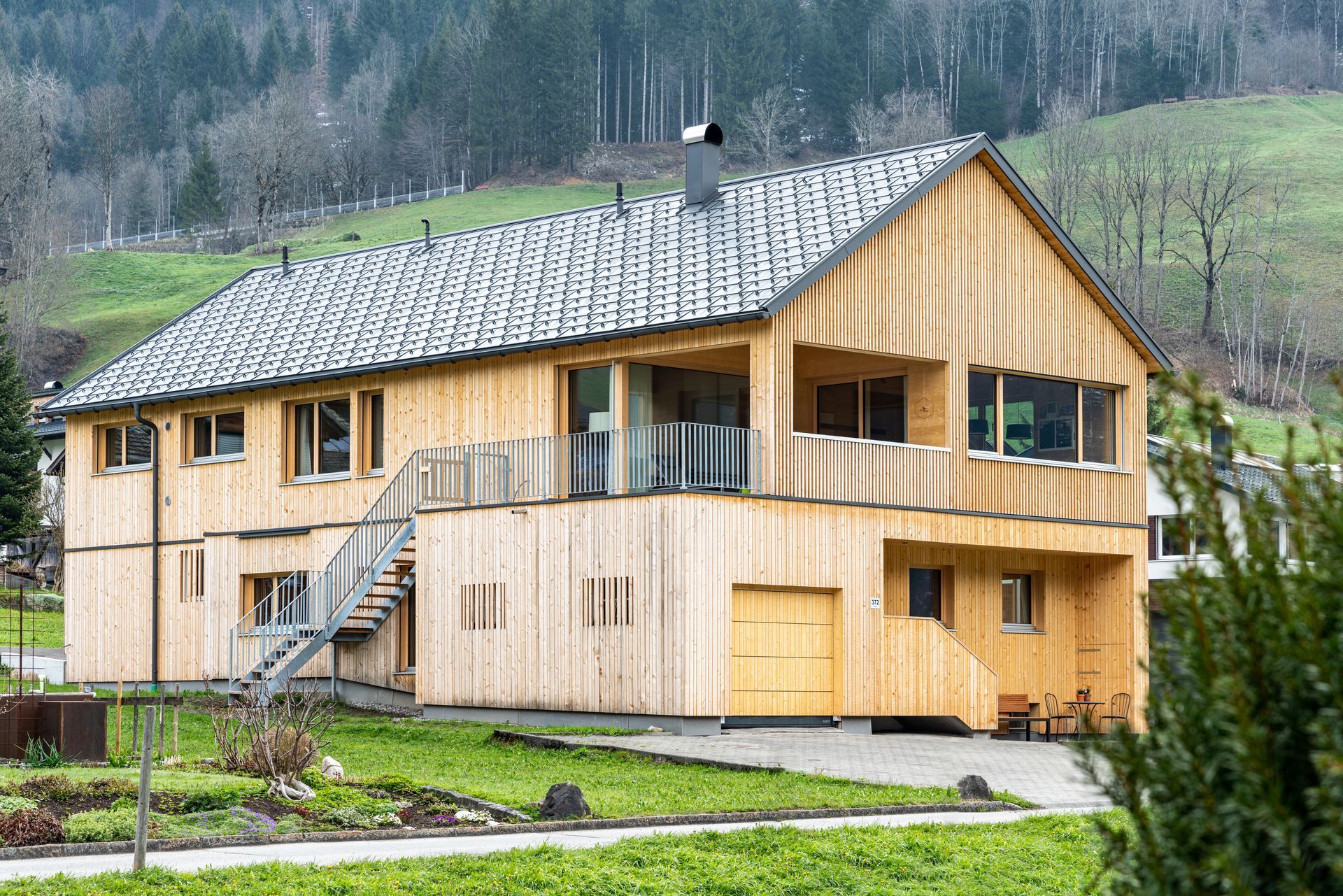 Auf einem üppig grünen Hügel steht ein großes Holzhaus.