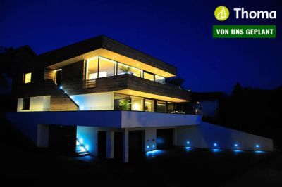 Ein großes Haus mit vielen Fenstern ist nachts beleuchtet