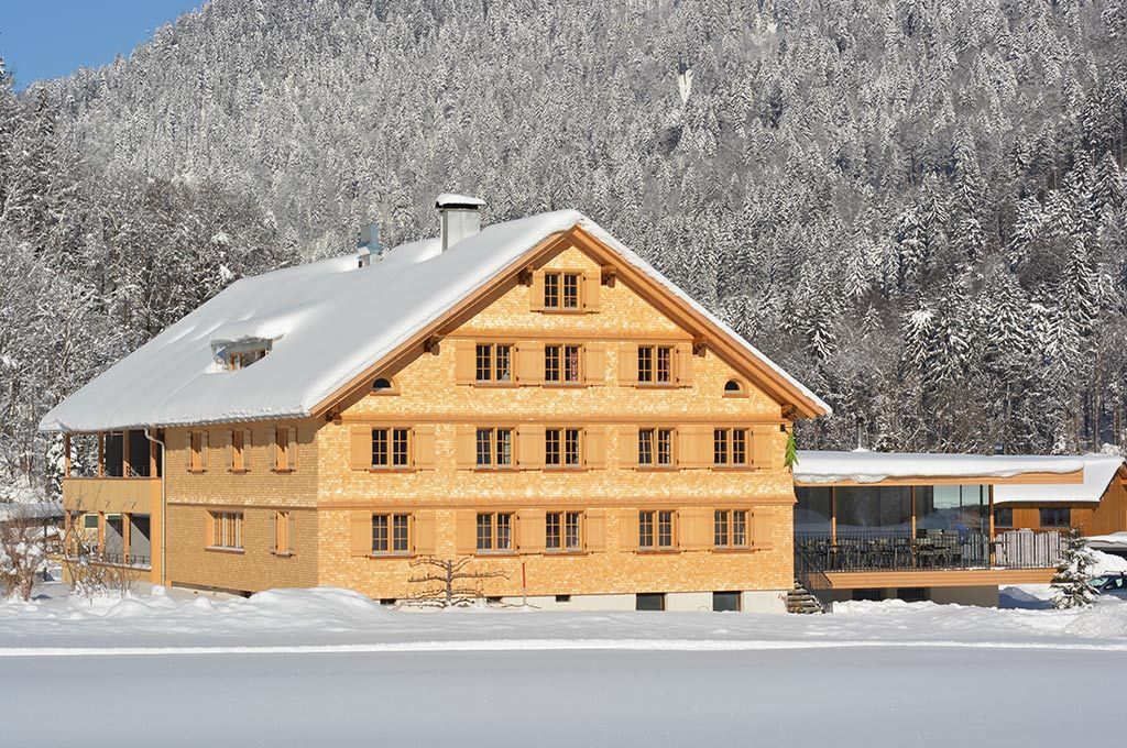 Ein großes Holzhaus ist von Schnee und Bergen umgeben