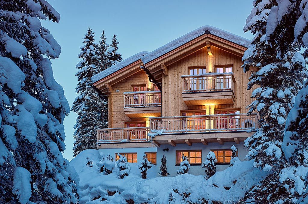 Ein großes Holzhaus ist von schneebedeckten Bäumen umgeben