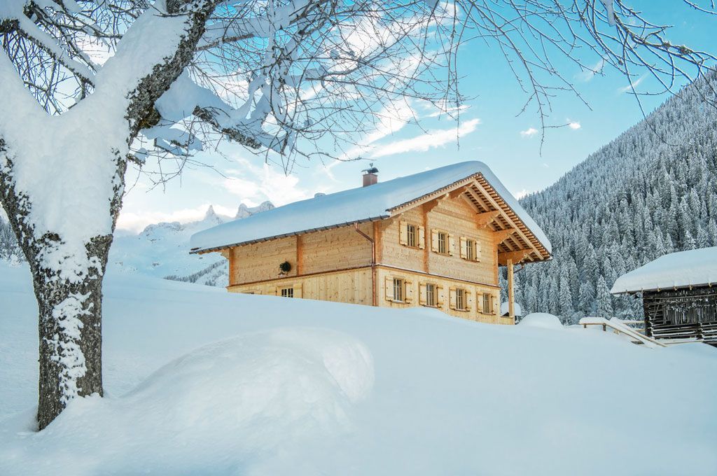 Ein Holzhaus steht inmitten eines schneebedeckten Feldes.