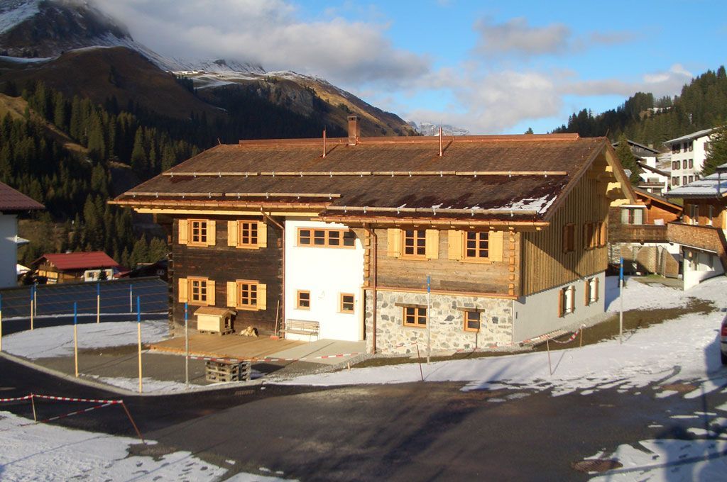 Ein großes Haus ist von Schnee und Bergen umgeben