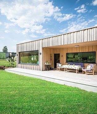 Ein großes Holzhaus mit einer großen Wiese davor.