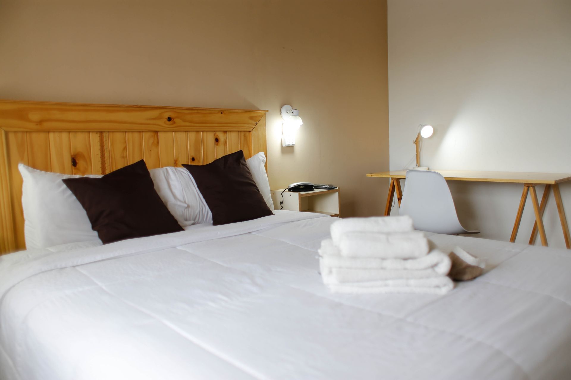 Un dormitorio con cama, escritorio, silla y toallas sobre la cama.
