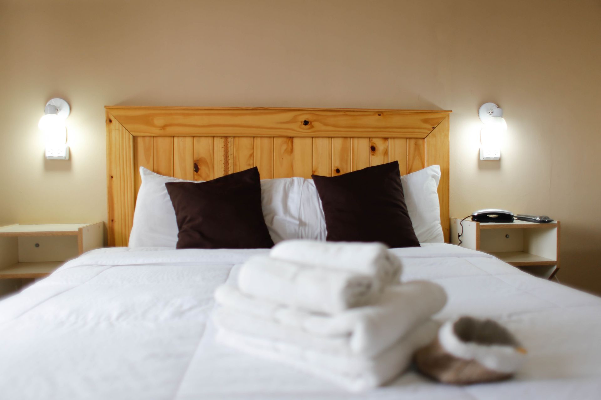 Una cama con cabecera de madera y almohadas en una habitación de hotel.