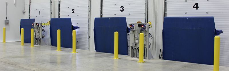 A row of loading docks in a warehouse with yellow poles.