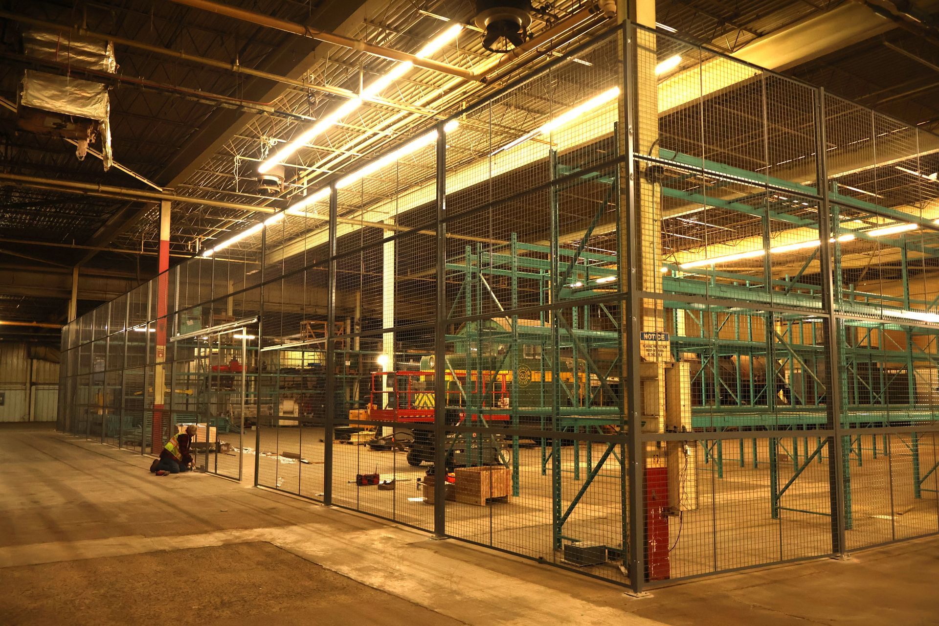 A large warehouse with lots of shelves and a fence around it