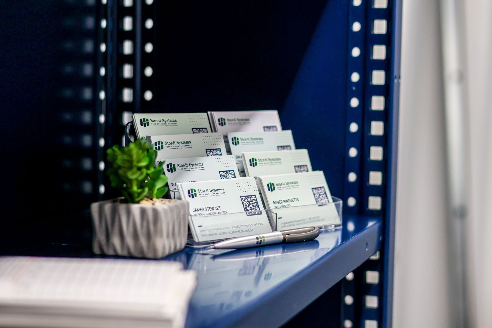 A shelf with business cards and a pen on it.