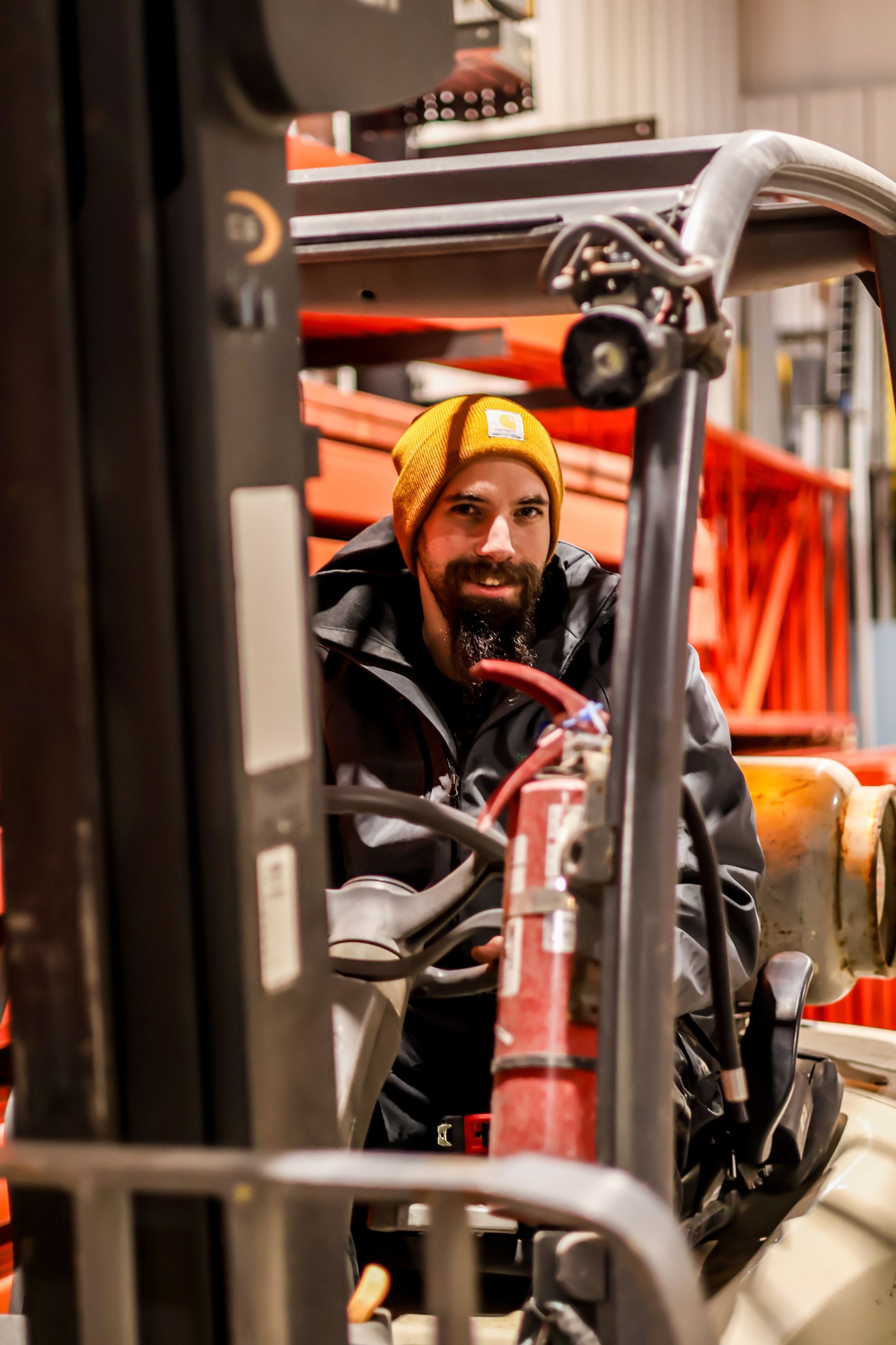 A man is sitting in a forklift in a warehouse holding a fire extinguisher.