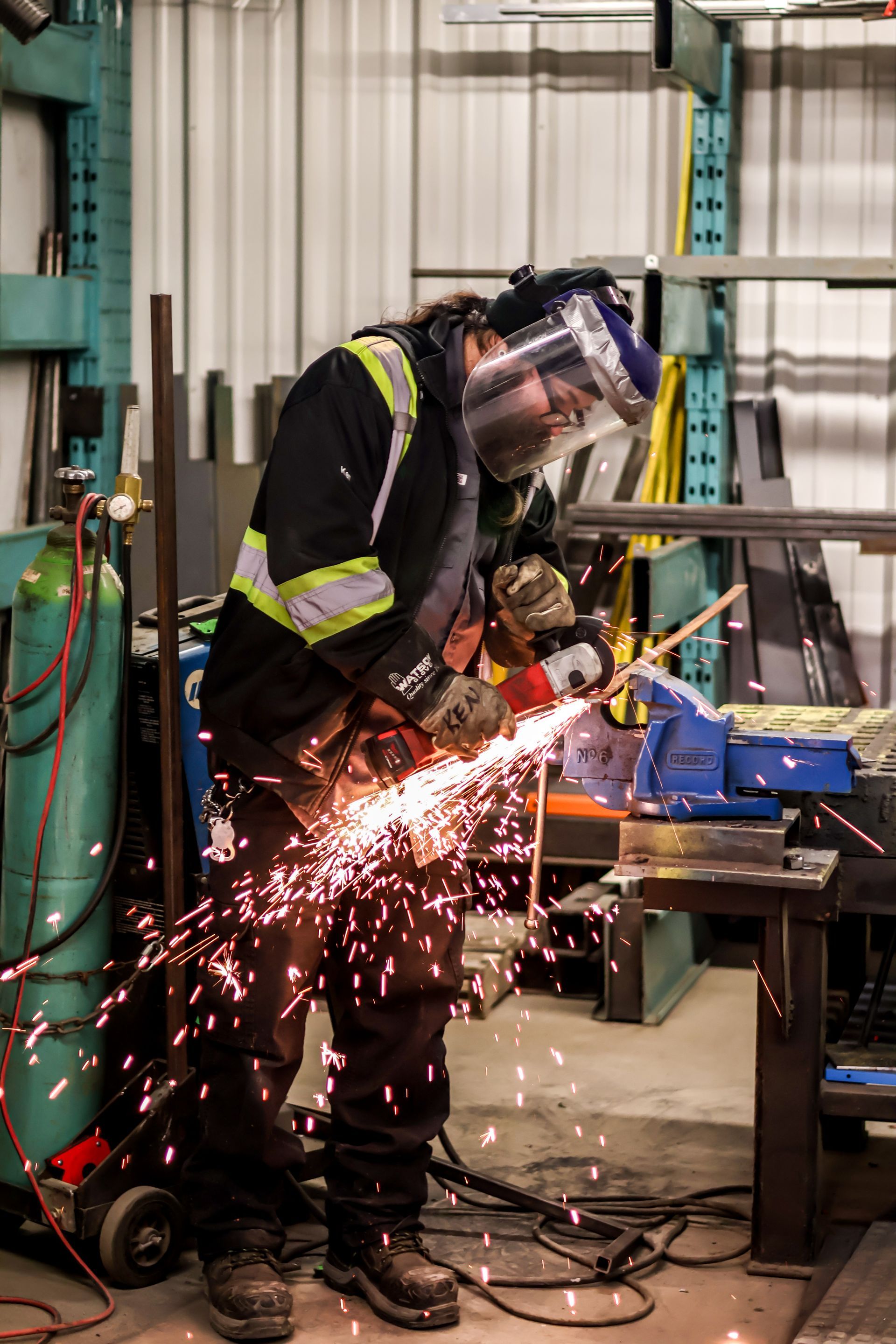 A man is welding a piece of metal in a factory.