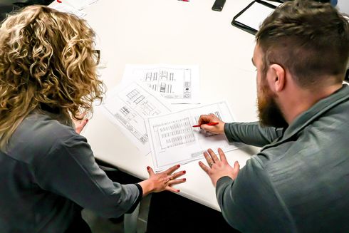 A man and a woman are sitting at a table looking at a blueprint.