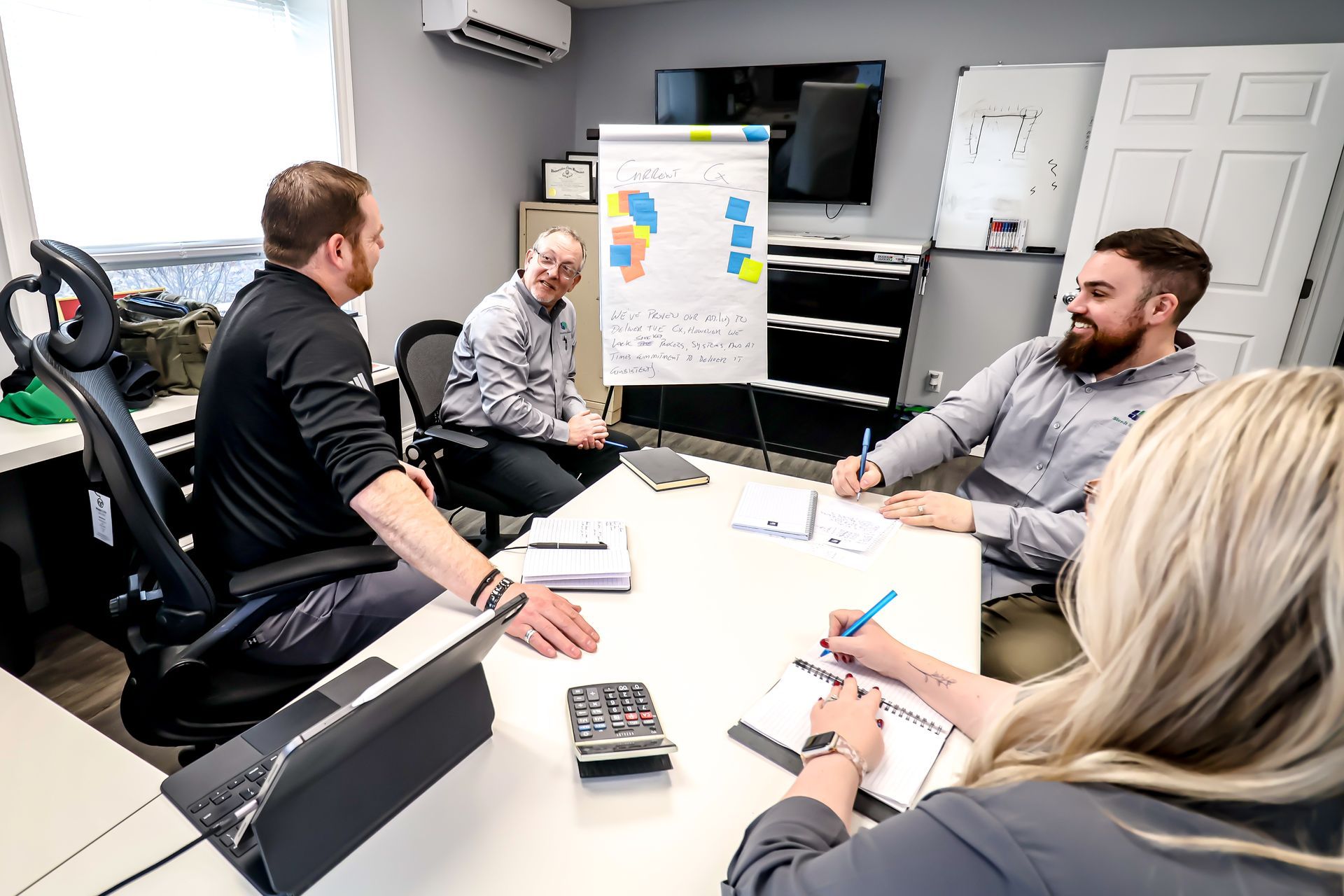 A group of people are sitting around a table in a conference room having a meeting.