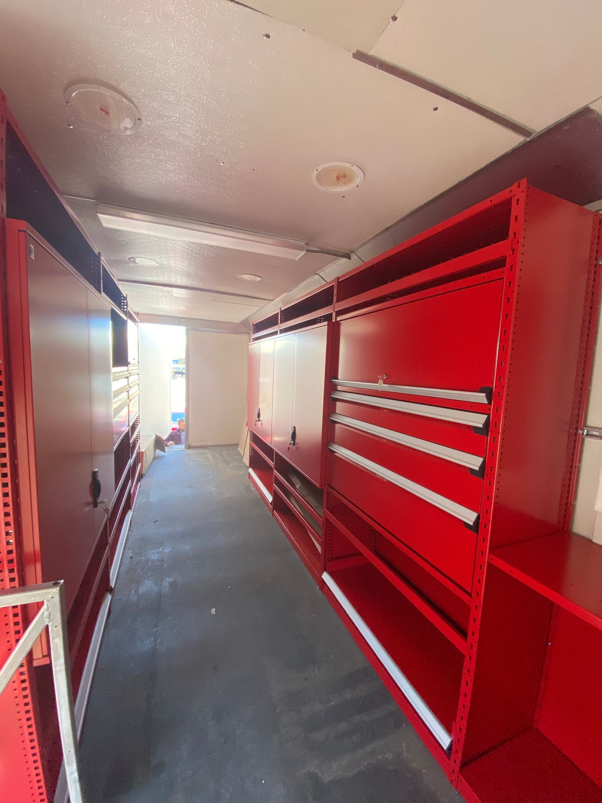 A long hallway filled with red shelves and cabinets.