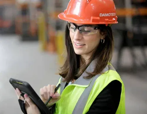 Stor-it Systems Worker in orange hard hat and safety vest using a tablet in a warehouse.